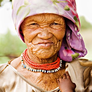 A Basarwa elder in a floral headscarf and beaded necklaces